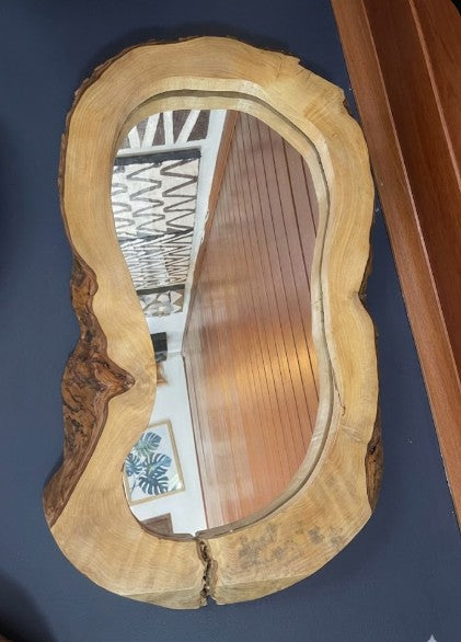 Wooden mirror with natural edge design on a blue wall
