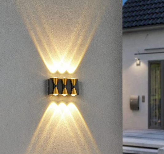 Stylish Amangazini 3 way wall sconce casting warm light patterns on a modern exterior wall