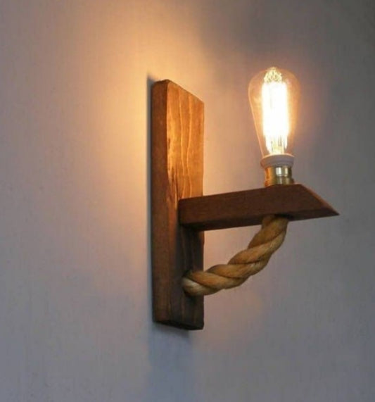 Wooden wall sconce with a rope design and lit bulb on a plain wall.