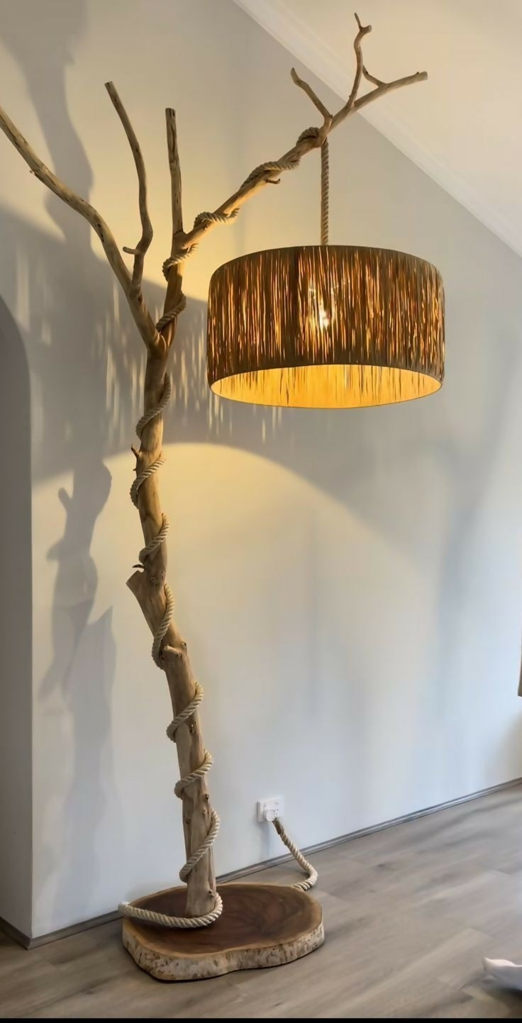 Floor lamp with natural branch design and brown lampshade against a white wall.
