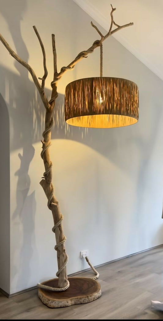 Floor lamp with natural branch design and brown lampshade against a white wall.