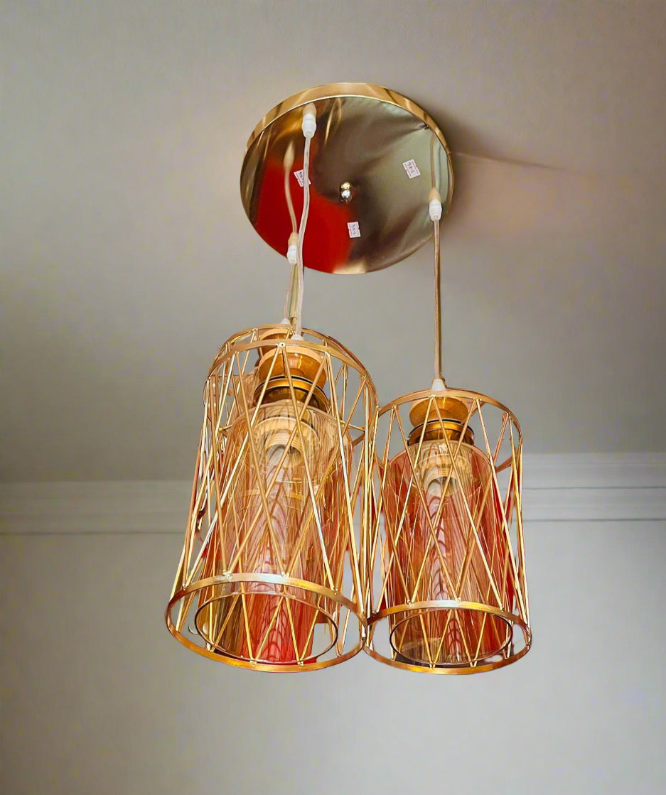 Gold pendant lights hanging from a ceiling with a wall in the background