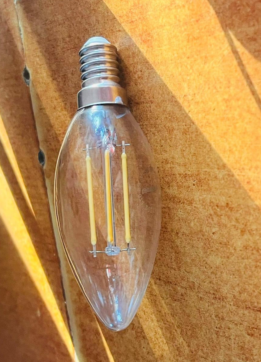 Clear light bulb on a wooden surface with tools in the background