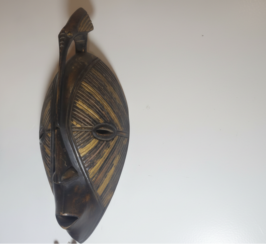 Wooden mask with intricate carvings on a white background