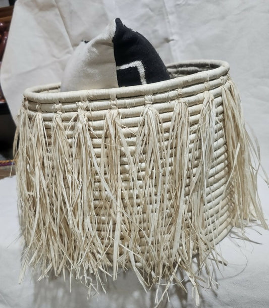 Woven basket with tassels containing a black and white sock on a light background
