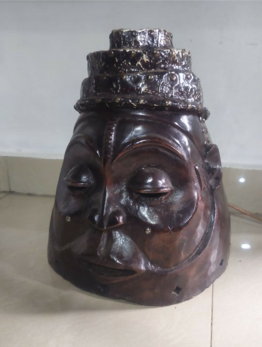 Wooden mask with a silver crown on a light-colored surface
