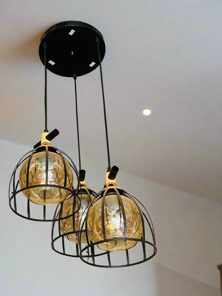 Amangazini Art Deco pendant light with three golden glass shades in a black cage design