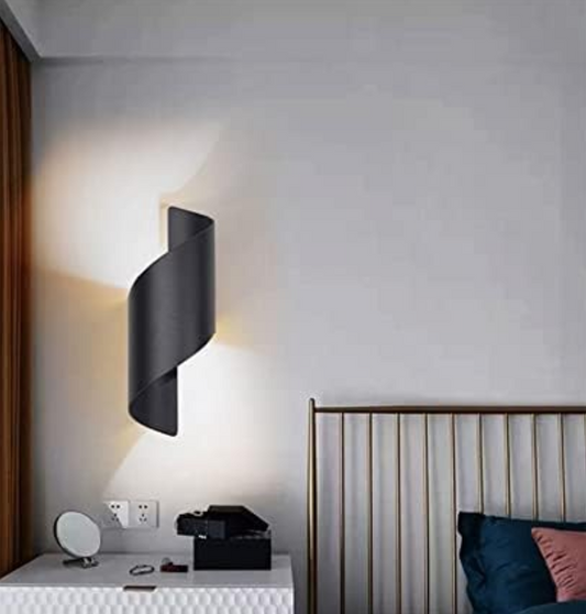 Amangazini black spiral wall sconce adding modern elegance to a bedroom with soft lighting