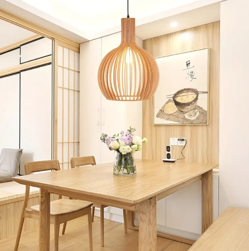 Amangazini handcrafted wood light pendant hanging above a wooden dining table with flowers