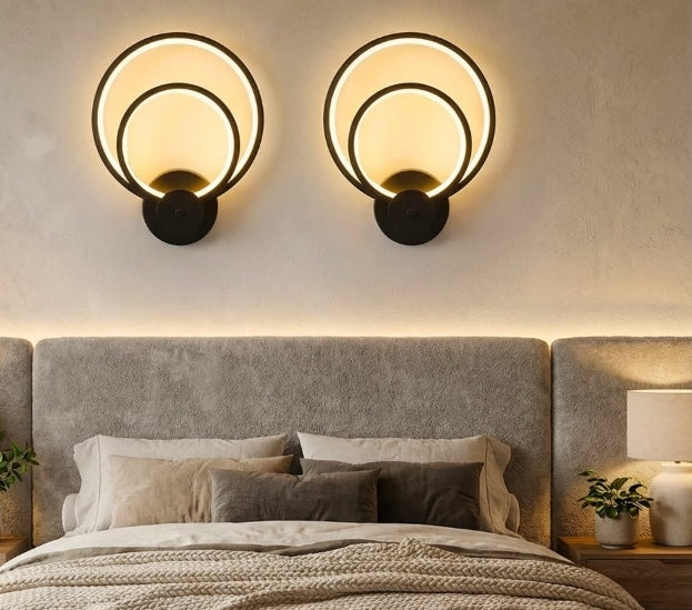 Two circular wall lights above a bed in a bedroom setting.