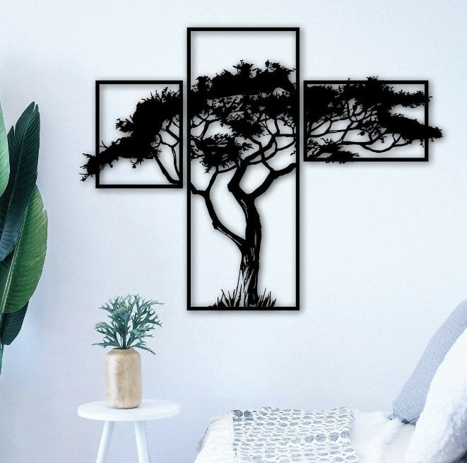 Set of three black tree silhouettes on a white wall with a plant and chair in the foreground.