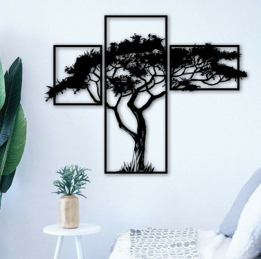 Set of three black tree silhouettes on a white wall with a plant and chair in the foreground.