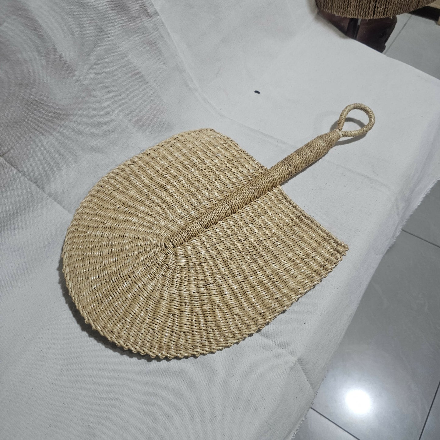 Woven fan with a handle on a white surface