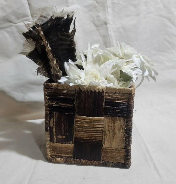 Decorative box with feathers and white flowers on a light background