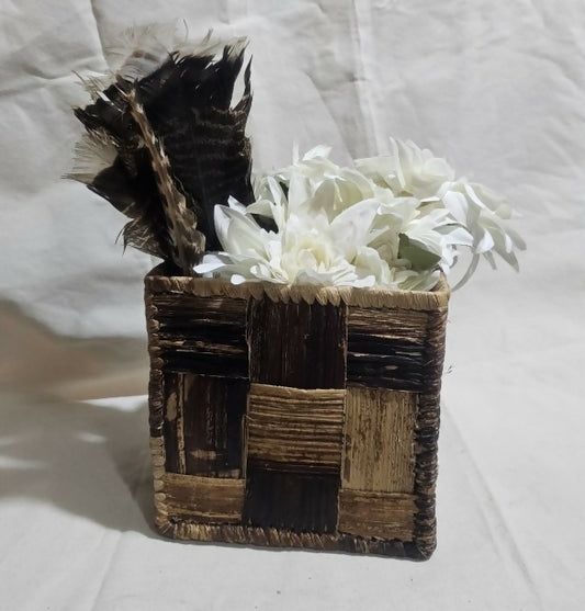 Decorative box with feathers and white flowers on a light background