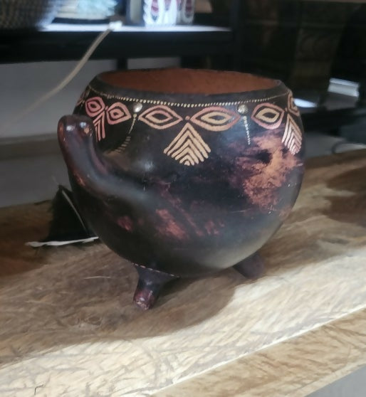 Decorative ceramic pot with tribal patterns on a wooden surface