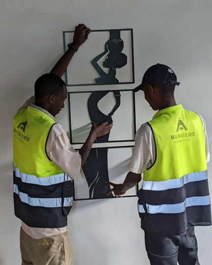 Two individuals in high-visibility vests working on a wall art installation.