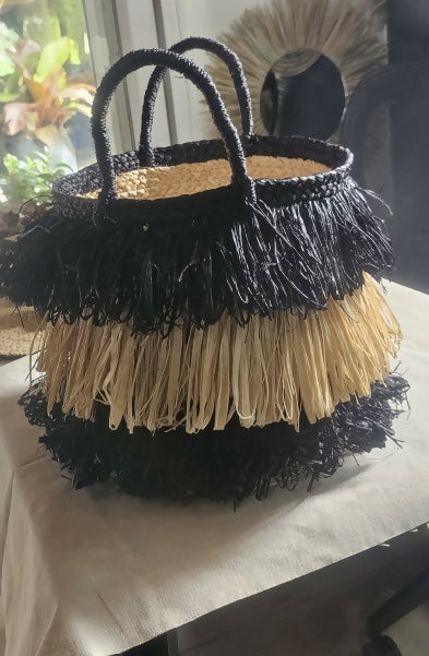 Two layered handbag with black and beige fringes on a table.