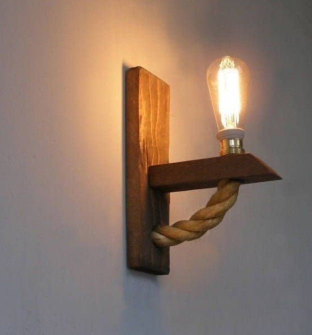 Wooden wall sconce with a rope design and lit bulb on a plain wall.