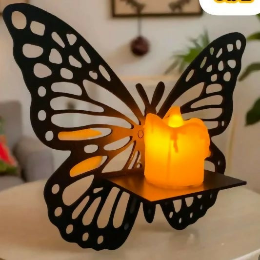 Butterfly-shaped candle holder with a lit candle inside on a table.