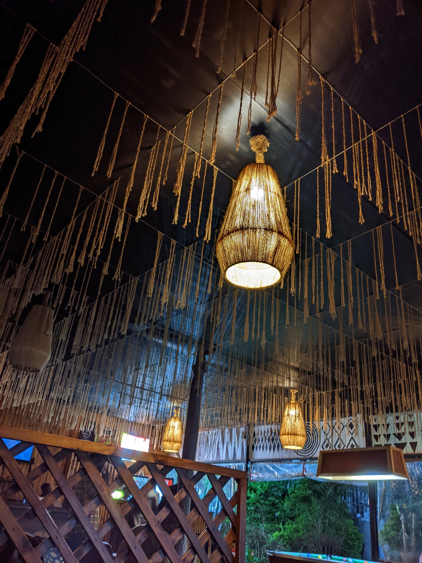 Decorative ceiling light fixture with hanging strands in a dimly lit room.