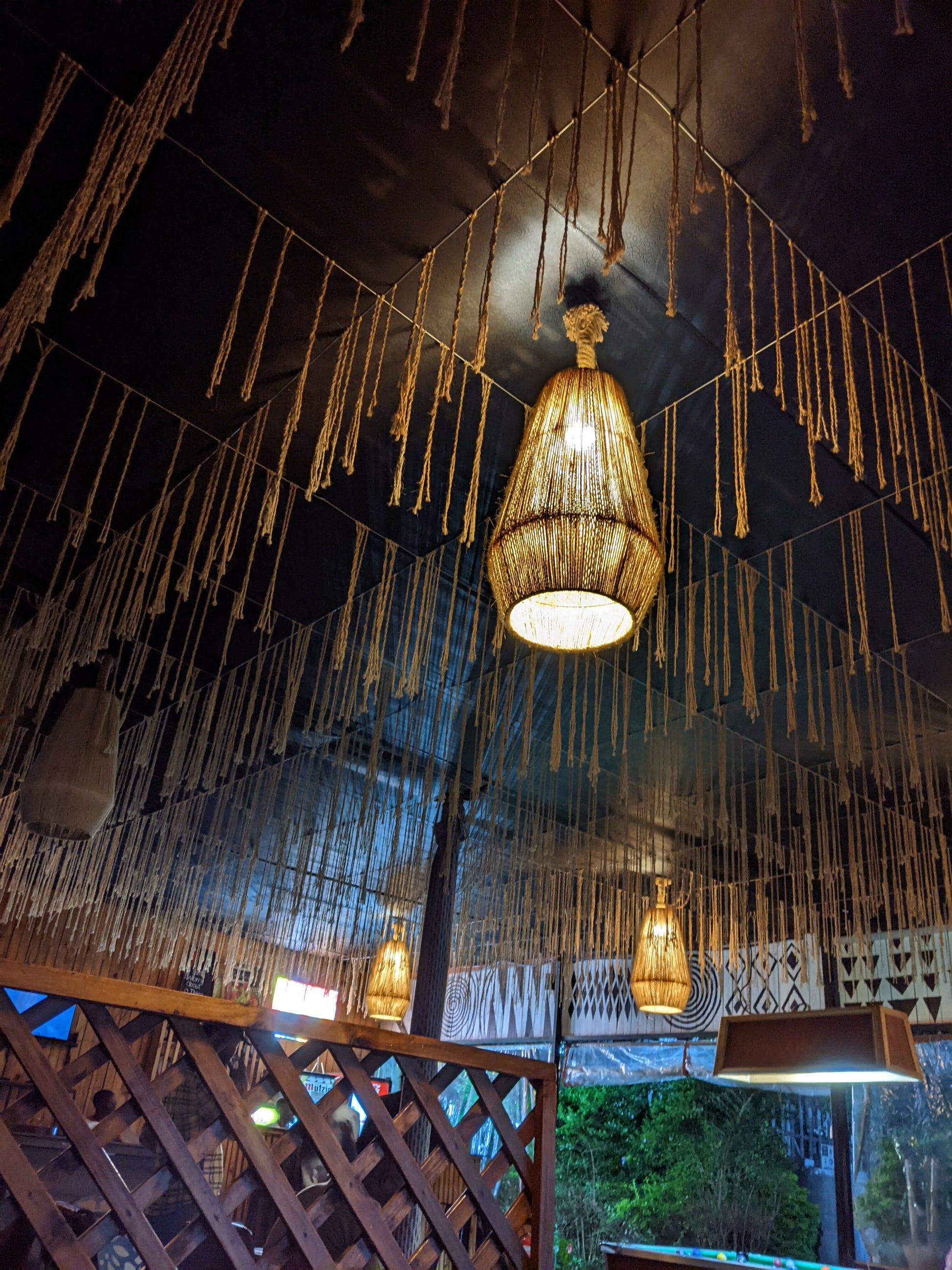 Decorative ceiling light fixture with hanging strands in a dimly lit room.