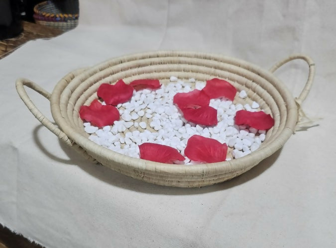 Wicker basket with red petals and white stones on a light background