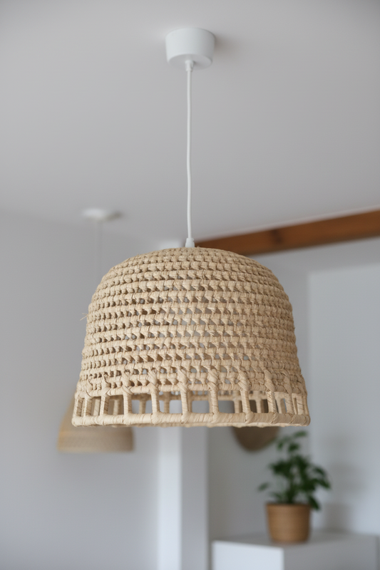 Woven lampshade hanging from a ceiling with a neutral background