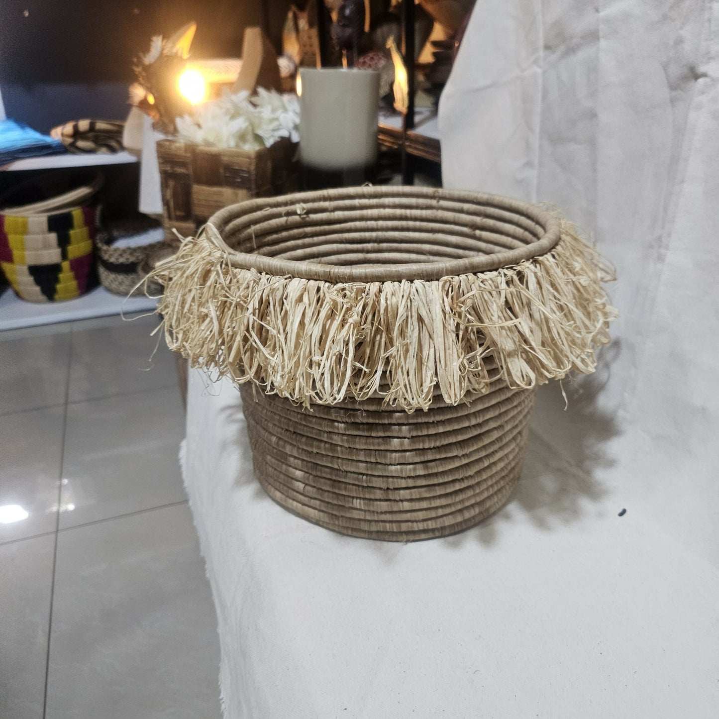 Woven basket with tassels on a white surface