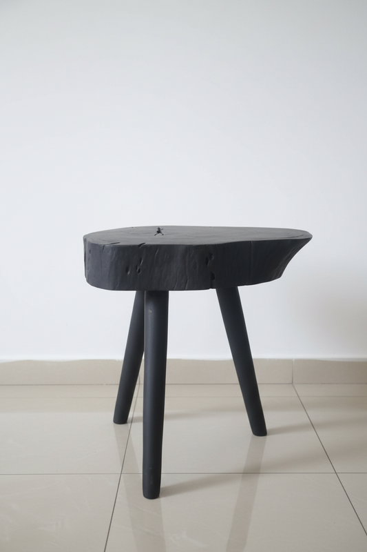 Black three-legged stool on a tiled floor with a blurred background