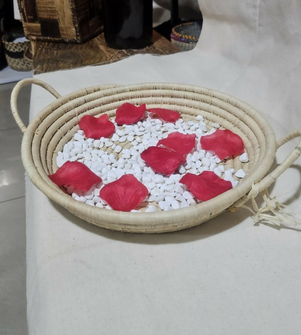 basket with red rose petals and white stones on a light surface