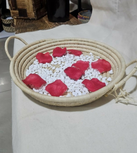 basket with red rose petals and white stones on a light surface