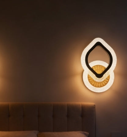 Modern wall light fixture on a dark wall with a bed in the foreground