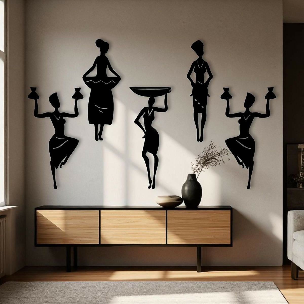 Black silhouette wall art of women on a wall above a wooden console table.