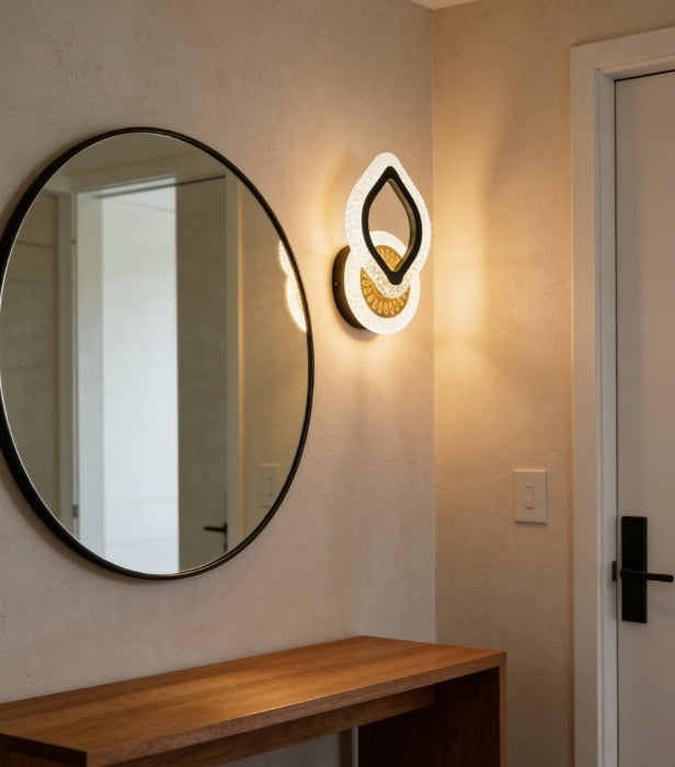 Round mirror on a wall with a modern light fixture above it in a room.