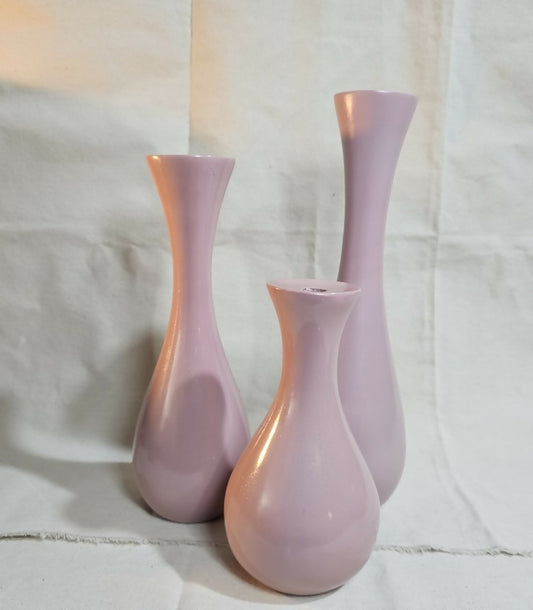 Three pink vases of different heights on a light fabric background