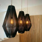 Three black pendant lights hanging in a room with a wooden panel background.