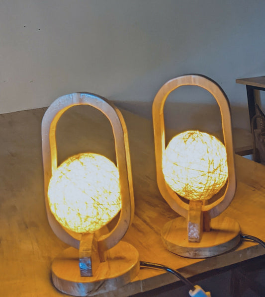 Two wooden table lamps with round, textured lampshades on a wooden surface.