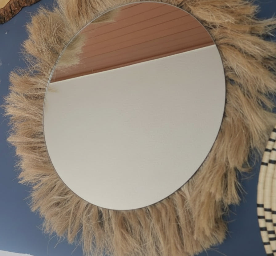 Round mirror with a natural fiber frame on a blue wall
