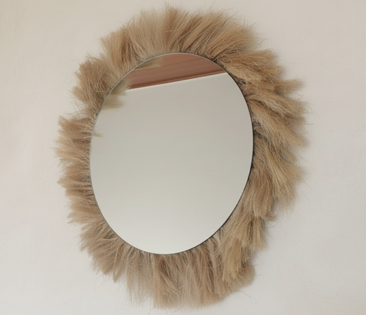 Round mirror with a fluffy, brown faux fur frame on a plain wall.