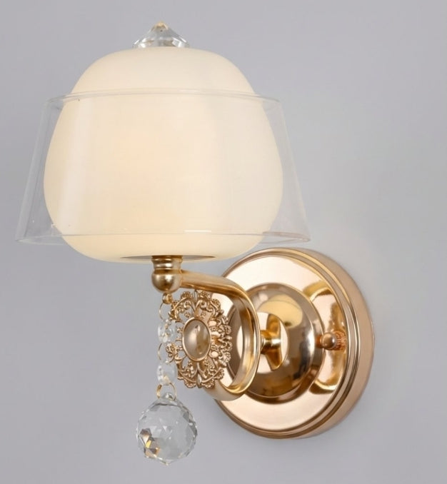 Wall-mounted light fixture with gold finish and decorative crystal on a gray background