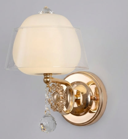 Wall-mounted light fixture with gold finish and decorative crystal on a gray background
