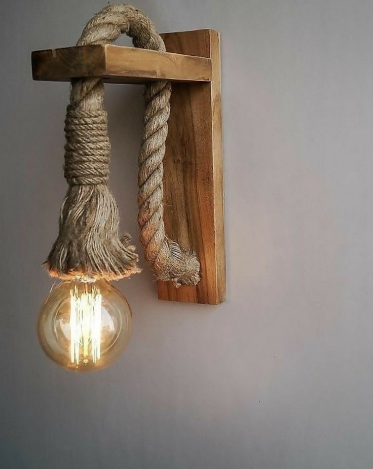 Wooden wall sconce with rope design and lit bulb against a gray background