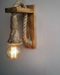 Wooden wall sconce with rope design and lit bulb against a gray background