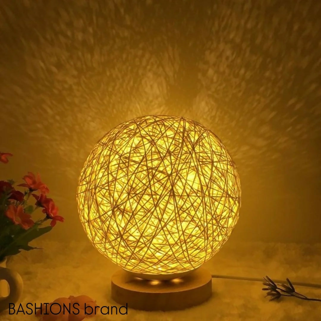 Woven ball lamp emitting a warm glow on a textured surface with 'BASHIONS' brand visible.