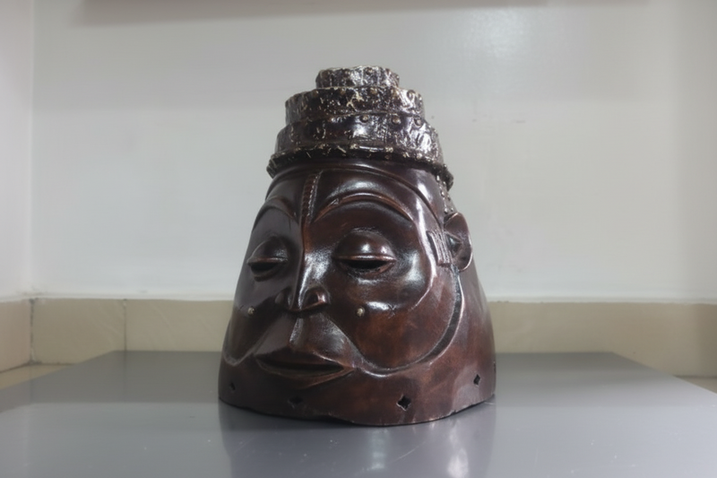 Wooden mask with a crown on a flat surface against a white wall