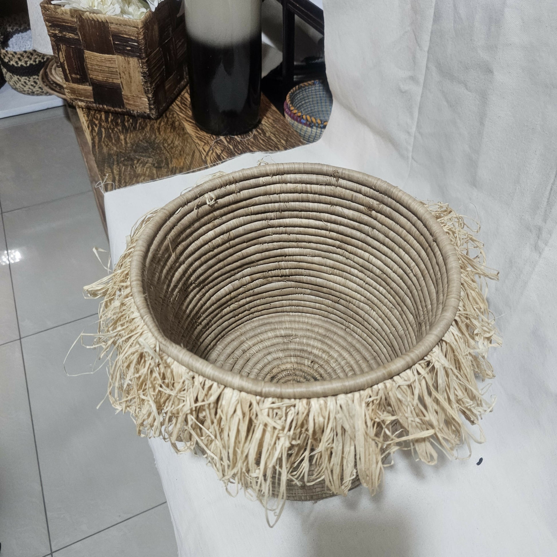 Woven basket with fringe on a white surface