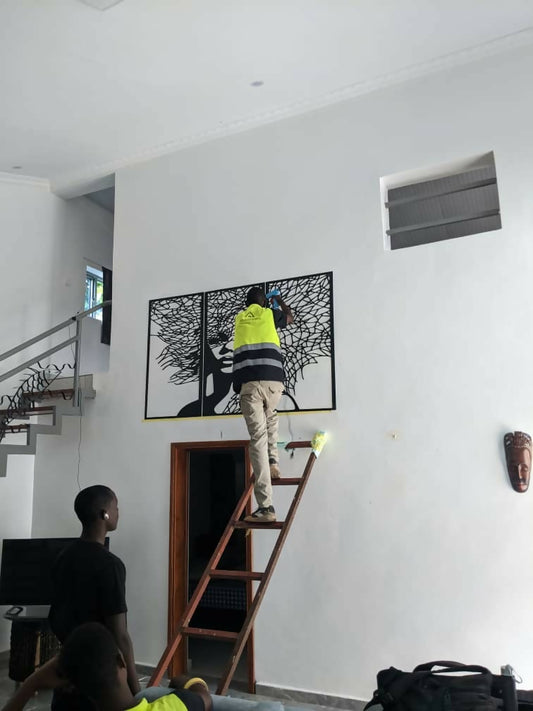 Person on a ladder installing artwork in a modern home interior.