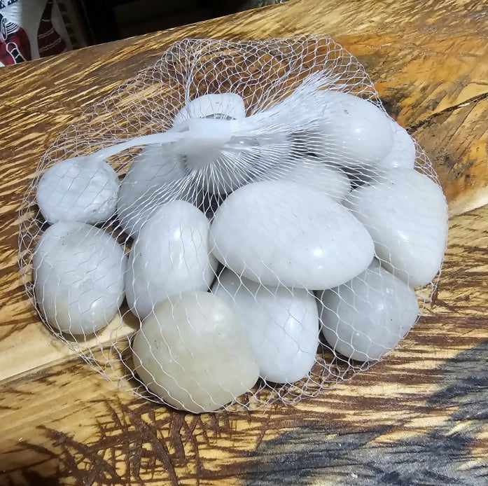 White stones in a mesh bag on a wooden surface