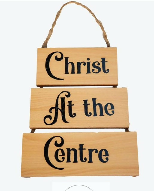 Wooden sign with 'Christ At the Centre' text on a white background